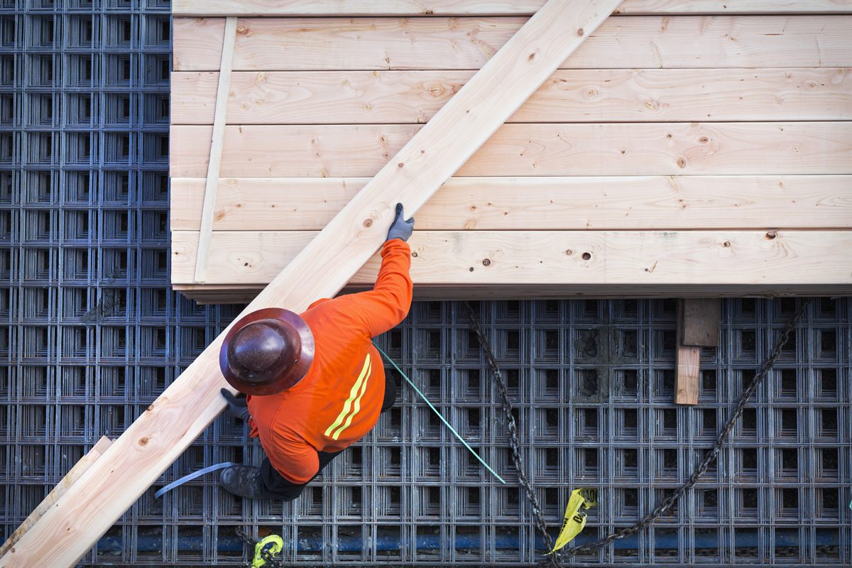 Worker lifting wood board on site